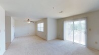 Located at Whiton Hills 522, this two-floor residence offers a well-designed layout that balances comfort and functionality across both levels. The main living area is spacious and open, featuring plush wall-to-wall carpeting that adds warmth underfoot. A ceiling fan with integrated lighting provides both air circulation and ambient illumination, while neutral-toned walls create a clean, versatile backdrop throughout.

Natural light flows generously into the living space through a standard window on one side and a large sliding glass door fitted with vertical blinds on the other. The sliding door provides direct access to the outdoors, offering views of surrounding greenery and allowing for seamless indoor-outdoor connectivity. Overhead, recessed ceiling vents ensure consistent climate control throughout the space.

The overall design is practical and understated, with a neutral color palette and simple finishes that allow for easy personalization. The two-floor configuration provides a clear separation between living and private areas, making effective use of the available footprint. This residence at Whiton Hills 522 presents a straightforward, functional living environment well-suited for a variety of occupants.