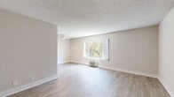 Located at 5353 Baltimore Dr in La Mesa, CA, this 2-bedroom, 1-bathroom unit offers a well-organized single-floor layout designed for comfortable everyday living. The open living room is bright and airy, featuring light wood-style flooring, neutral warm-toned walls, a ceiling fan, a wall-mounted HVAC unit, and a large window that frames views of surrounding greenery. An adjacent area provides additional flexible living space with the same flooring and ample natural light. The galley-style kitchen is thoughtfully updated with crisp white cabinetry, gray quartz-style countertops, a subway tile backsplash, and a full suite of stainless steel appliances including a range, microwave, refrigerator, and dishwasher. Both bedrooms are carpeted in a neutral gray tone and receive natural light through window blinds. The primary bedroom is generously sized and features mirrored sliding closet doors that enhance the sense of space. The full bathroom is clean and modern, with white cabinetry, a quartz-style vanity top, brushed nickel fixtures, and a tub-shower combination. A hallway connects the main living areas to the private quarters. Textured ceilings and consistent light wood flooring in the common areas tie the unit together with a cohesive, move-in-ready aesthetic.