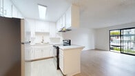 Located at 2125 Westinghouse St in San Diego, California, this single-floor unit offers a clean, modern interior with a well-considered open-concept design. The kitchen is a standout feature, outfitted with crisp white cabinetry, light quartz countertops, a stainless steel refrigerator, an electric range, and an under-cabinet range hood. A skylight overhead floods the kitchen with natural light, enhancing the bright, airy atmosphere throughout. Light wood-look flooring runs consistently through the kitchen and into the adjacent living area, creating a seamless flow between spaces. A peninsula counter separates the kitchen from the open living space, which offers a generous footprint and is further complemented by a ceiling fan. The bathroom is finished in a clean, all-white palette, complete with a full-size soaking tub and shower combo with chrome fixtures. The overall interior aesthetic is minimalist and neutral, providing a versatile canvas. Outside, the property features covered carport parking, landscaped grounds with palm trees, and access to a multi-unit residential community — all consistent with the convenience-oriented character of the Linda Vista neighborhood in San Diego.