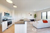 Located at 72 South Essex Avenue in Orange, NJ, this well-appointed 2-bedroom, 2-bathroom residence offers a thoughtfully designed single-floor layout. The open-concept living area seamlessly integrates the kitchen, dining, and living spaces, creating an airy and connected environment. Large black-framed windows flood the living room with natural light and frame panoramic views of the surrounding cityscape and treetops.

The kitchen is outfitted with stainless steel appliances — including a gas range, microwave, and refrigerator — complemented by light wood cabinetry, a subway tile backsplash, and a spacious island with a dark countertop and built-in sink, ideal for both cooking and casual dining. Light wood-tone flooring runs throughout the main living areas, adding warmth and continuity.

The primary bedroom is generously sized, featuring dual windows with outdoor views and ample natural light. The second bedroom is equally bright, also benefiting from large windows. Three closets, including a walk-in with built-in rods and shelving, provide excellent storage. Both bathrooms are clean and modern, with one featuring a full soaking tub and tiled surround. Additional utility and laundry rooms complete this practical and stylish home.