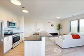 Located at 72 South Essex Avenue in Orange, NJ, this well-appointed 2-bedroom, 2-bathroom residence offers a thoughtfully designed single-floor layout. The open-concept living area seamlessly integrates the kitchen, dining, and living spaces, creating an airy and connected environment. Large black-framed windows flood the living room with natural light and frame panoramic views of the surrounding cityscape and treetops.

The kitchen is outfitted with stainless steel appliances — including a gas range, microwave, and refrigerator — complemented by light wood cabinetry, a subway tile backsplash, and a spacious island with a dark countertop and built-in sink, ideal for both cooking and casual dining. Light wood-tone flooring runs throughout the main living areas, adding warmth and continuity.

The primary bedroom is generously sized, featuring dual windows with outdoor views and ample natural light. The second bedroom is equally bright, also benefiting from large windows. Three closets, including a walk-in with built-in rods and shelving, provide excellent storage. Both bathrooms are clean and modern, with one featuring a full soaking tub and tiled surround. Additional utility and laundry rooms complete this practical and stylish home.