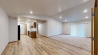 This single-floor, 2-bedroom, 2-bathroom residence is thoughtfully laid out to maximize both comfort and functionality. The open-concept living and kitchen area serves as the heart of the home, featuring light hardwood-style flooring that flows seamlessly throughout the main living spaces. The kitchen is equipped with warm wood cabinetry, light stone-look countertops, a stainless steel refrigerator, and recessed lighting, all oriented along a galley-style run that opens to the living area. The living room benefits from vaulted ceilings and recessed lighting, creating an airy, open ambiance, with a sliding glass door fitted with vertical blinds that invites natural light into the space. Plush neutral carpeting defines the living and bedroom areas, adding warmth underfoot. The spacious primary bedroom offers generous room for furnishings, accented by a window with blinds providing natural light. The second bedroom is similarly carpeted and well-proportioned. Both bathrooms are finished with wood vanities, stone-look countertops, and tub-shower combinations. A dedicated laundry area with a stacked washer and dryer adds everyday convenience. Three closets throughout the home provide ample storage, and a hallway connects the private quarters to the main living areas efficiently.