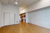 Located at 2065 S River Pkwy in Portland, Oregon, this single-floor studio unit offers a well-designed open layout that efficiently combines living and kitchen spaces. The unit features warm hardwood-style flooring throughout, contributing to a cohesive and inviting ambiance.

The kitchen is thoughtfully appointed with rich warm-toned wood cabinetry extending from floor to ceiling, providing generous storage. Light quartz countertops offer ample prep space, and the full suite of white appliances includes a refrigerator, electric range, dishwasher, and an under-cabinet range hood. A stainless single-basin sink completes the functional kitchen setup.

The open living area is bright and airy, with notably high ceilings that lend a sense of spaciousness beyond the unit's compact footprint. A ceiling fan with integrated lighting serves as a central fixture, while recessed lighting and a large window fitted with vertical blinds bring in natural light and further enhance the open feel. A sliding-door closet provides convenient built-in storage.

The bathroom features a modern vanity with a stone-speckled quartz countertop, an undermount sink, warm wood cabinetry with brushed hardware, and dual mirrors. Clean white walls and neutral tile flooring complete the polished look throughout.