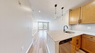 Located at 1 Richmond St in New Brunswick, NJ, this well-appointed one-bedroom, one-bathroom residence offers a thoughtfully designed open-concept layout. The combined kitchen and living area forms the heart of the home, featuring light hardwood flooring that extends throughout the main living spaces and creates a bright, cohesive atmosphere. Large windows at the end of the living room invite generous natural light and offer views of surrounding greenery.

The kitchen is equipped with warm-toned wood cabinetry, a classic white subway tile backsplash, and sleek quartz countertops that extend into a peninsula with seating potential. Stainless steel appliances — including a refrigerator, range, microwave, and dishwasher — complete the space, accented by a matte black faucet that adds a contemporary touch.

The bedroom is a comfortable, well-proportioned retreat finished with plush carpeting and a window overlooking outdoor greenery, providing a calm and private atmosphere. A dedicated closet offers convenient storage.

The bathroom features neutral large-format tile flooring, a tiled tub surround, and a clean, modern aesthetic. Recessed lighting throughout the unit enhances the overall sense of brightness and polish in this move-in-ready New Brunswick residence.