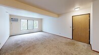 Located at 1103 Michigan Ave E in Battle Creek, Michigan, this two-bedroom, one-bathroom unit offers a practical and efficiently organized single-floor layout. The open-concept living, dining, and kitchen area forms the heart of the home, providing a comfortable and connected space for everyday living. The living area features plush carpeting, a ceiling fan, and a large window that invites natural light and views of the surrounding greenery. The galley-style kitchen is well-equipped with warm wood cabinetry, light countertops, a double stainless steel sink, and white appliances including a refrigerator, electric range, microwave, and dishwasher. Tile flooring runs through the kitchen, complementing the cabinetry tones. A dedicated laundry area with a washer and dryer is conveniently located within the unit. Both bedrooms are carpeted and generously sized, each featuring ceiling fans, closets with wood-panel doors, and windows that allow natural light. The primary bedroom is notably spacious and well-proportioned. The bathroom includes a full tub/shower combination, a toilet, and tile flooring. A hallway connects all rooms, and two closets provide ample storage throughout the unit.
