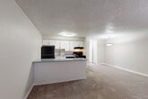 Located at 1066 S Dahlia St in Glendale, Colorado, this one-bedroom residence offers a thoughtfully arranged single-floor layout that maximizes its compact footprint. The open-concept design seamlessly connects the kitchen and living area, creating a cohesive and functional shared space. The kitchen is equipped with black appliances, including a refrigerator, electric range with oven, and dishwasher, complemented by crisp white cabinetry that provides ample storage. A peninsula counter separates the kitchen from the living area, offering additional workspace and a natural transition between the two zones. The kitchen features wood-look flooring, while the living area is finished with neutral wall-to-wall carpeting that continues into the bedroom. The bedroom is a comfortably sized retreat featuring a large sliding-door closet, a window that allows natural light and neighborhood views, and a baseboard heating unit. Textured ceilings are consistent throughout the space, contributing to its understated character. The neutral color palette of warm beiges and clean whites throughout gives the home a bright, cohesive aesthetic. The layout is efficient and well-suited for those seeking a straightforward, low-maintenance living space in the heart of Glendale.