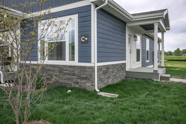 Charming blue house exterior with modern stone accents and lush green lawn. - Grace Lane Apartments