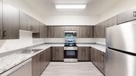 This 2-bedroom, 2-bathroom single-floor unit offers a thoughtfully designed layout that makes efficient use of its space. Light wood-style flooring runs consistently throughout, lending a clean and cohesive aesthetic to every room.

The kitchen is a standout feature, configured in a U-shape that maximizes counter and storage space. It is outfitted with dark wood-toned cabinetry, light granite-style countertops, and a full suite of stainless steel appliances including a range, over-the-range microwave, dishwasher, and refrigerator. Bright overhead lighting enhances the workspace.

The living room is bright and open, featuring a door and window that invite natural light and offer direct views of lush greenery outside. A hallway connects the main living areas to the private quarters, which include two well-sized bedrooms. Both bedrooms feature windows overlooking verdant outdoor scenery, filling the rooms with natural light and a sense of calm. The primary bedroom offers a comfortable footprint suited for a full furniture arrangement.

The two bathrooms are finished with consistent materials — dark wood vanities with stone-style countertops, light tile-style flooring, and clean white walls. One bathroom includes a full soaking tub with shower combination. A dedicated closet provides additional storage within the unit.