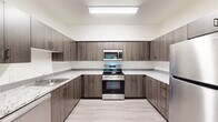 This 2-bedroom, 2-bathroom single-floor unit offers a thoughtfully designed layout that makes efficient use of its space. Light wood-style flooring runs consistently throughout, lending a clean and cohesive aesthetic to every room.

The kitchen is a standout feature, configured in a U-shape that maximizes counter and storage space. It is outfitted with dark wood-toned cabinetry, light granite-style countertops, and a full suite of stainless steel appliances including a range, over-the-range microwave, dishwasher, and refrigerator. Bright overhead lighting enhances the workspace.

The living room is bright and open, featuring a door and window that invite natural light and offer direct views of lush greenery outside. A hallway connects the main living areas to the private quarters, which include two well-sized bedrooms. Both bedrooms feature windows overlooking verdant outdoor scenery, filling the rooms with natural light and a sense of calm. The primary bedroom offers a comfortable footprint suited for a full furniture arrangement.

The two bathrooms are finished with consistent materials — dark wood vanities with stone-style countertops, light tile-style flooring, and clean white walls. One bathroom includes a full soaking tub with shower combination. A dedicated closet provides additional storage within the unit.