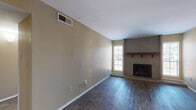 This single-floor unit offers a well-organized layout with distinct living, sleeping, and functional zones throughout. The spacious living room serves as the heart of the home, showcasing dark hardwood-style flooring, warm neutral-toned walls, and a striking brick fireplace flanked by two windows that allow natural light to fill the room. A hallway connects the main living area to the private quarters of the unit.

The galley-style kitchen is efficiently designed with rich, dark wood cabinetry lining both sides, complemented by dark granite countertops and a mosaic tile backsplash. A window above the end wall provides natural light, and the kitchen is equipped with a stainless steel sink, electric range, and dishwasher.

The bedrooms feature soft wall-to-wall carpeting, neutral warm-toned walls, and ceiling fans with integrated lighting, creating a comfortable atmosphere. Each room benefits from windows with blinds that offer both natural light and privacy.

Two bathrooms serve the unit. One features a tub-shower combination with white tile surround, a dark wood vanity with granite countertop, and wood-look flooring. The second bathroom includes a sliding-door shower enclosure and a similarly appointed granite-topped vanity. Both bathrooms maintain a clean, functional aesthetic consistent with the rest of the unit.