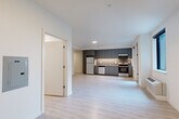 Located at 636 W 6th St in Vancouver, Washington, this efficiently designed single-floor unit offers a clean, modern aesthetic throughout. The open-concept kitchen and living area serves as the heart of the space, featuring light wood-style flooring that extends seamlessly through every room, crisp white walls, and abundant natural light streaming in through large windows and a glass-paned exterior door that opens to an outdoor view.

The kitchen is well-appointed with sleek gray flat-front cabinetry extending to the ceiling, stainless steel appliances including an electric range, dishwasher, and refrigerator, a light stone-finish countertop, and a tasteful tile backsplash. Recessed and under-cabinet lighting add a polished, functional touch.

The living area provides an open, flexible layout with a bright, neutral palette that enhances the sense of space. A dedicated closet with a full rod and shelving offers practical storage, complemented by a louvered utility door nearby.

The bathroom maintains the same contemporary style, showcasing gray cabinetry with brushed nickel hardware, a stone-finish vanity countertop with an undermount sink, a large mirror, and light wood-look tile flooring. Clean white walls and modern fixtures complete the refined, move-in-ready feel of this thoughtfully designed space.