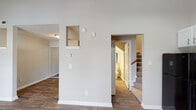 Located at 700 Grathwol Dr in Wilmington, NC, this two-story residence offers a well-planned layout designed for comfortable everyday living. The main level immediately impresses with soaring vaulted ceilings in the living area, accentuated by a ceiling fan and generous natural light streaming through large windows. Rich, dark hardwood-style flooring flows throughout the main level, lending warmth and cohesion to the space.

The kitchen is thoughtfully appointed with crisp white beadboard cabinetry, light countertops, and a full suite of black and stainless steel appliances, including a refrigerator, electric range, built-in microwave, and dishwasher. A pendant light overhead and an adjacent large window brighten the space considerably. A half bathroom tucked conveniently beneath the staircase serves the main level, featuring a vanity and clean, simple finishes.

A carpeted staircase with a warm wood handrail leads to the upper level, where two bedrooms offer plush carpet flooring and ceiling fans in each room. One bedroom features an interior window that overlooks the stairwell, adding an architectural detail that enhances the sense of openness. A dedicated utility area on the upper level houses the water heater and provides additional access panels for home systems.