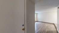 This single-story residence offers a well-organized layout with a variety of functional spaces connected by consistent wood-look flooring in the main living areas. The living room serves as a central focal point, distinguished by a striking floor-to-ceiling natural stone fireplace that adds character and warmth to the space. A sliding glass door with vertical blinds provides access to the outdoors and brings in natural light. A ceiling fan overhead contributes to the room's comfort and practicality.

The galley-style kitchen is efficiently designed, featuring warm wood cabinetry on both sides, granite-style countertops, and a full suite of black appliances including a refrigerator, electric range with overhead ventilation, and dishwasher. A recessed tray ceiling detail adds architectural interest to the kitchen area.

The bedrooms are carpeted for comfort and finished with neutral tones, textured ceilings, and panel-style closet doors. Each room offers ample wall space and standard overhead ventilation.

Two bathrooms serve the unit, both finished with wood-look flooring, warm wood vanity cabinetry, granite-style countertops, and tub-shower combinations. The overall aesthetic throughout the space is neutral and cohesive, with textured ceilings a consistent design element.
