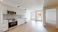 Located on Santa Monica Boulevard in the heart of West Los Angeles, this 2-bedroom, 1-bathroom unit offers a clean, modern aesthetic defined by a neutral palette and light wood-style flooring that runs throughout the entire space. The open-concept layout connects the kitchen and living area seamlessly, creating an efficient and welcoming flow. The kitchen is well-appointed with flat-front light gray cabinetry, a full suite of stainless steel appliances including a refrigerator, range, microwave, and dishwasher, a tile backsplash, and gold-accented fixtures that add a contemporary touch. Directional sconce lighting highlights the kitchen area with a stylish, modern flair. The living area is bright and airy, benefiting from a glass door that opens to a private balcony with outdoor views. Both bedrooms are finished in the same light tones, with the primary bedroom featuring a dedicated walk-in closet with built-in shelving, and the second bedroom offering a sliding door closet. Natural light filters in through well-placed windows, enhancing the open feel of each room. The bathroom features warm wood-toned cabinetry, a white countertop vanity with an arched mirror, and accessibility grab bars. A hallway connects all rooms, completing this thoughtfully designed, move-in-ready unit.