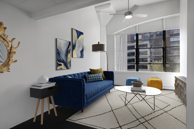 Sofá azul de la sala de estar con ventanas de fábrica - Ford Factory Lofts