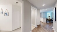 Located at 3400 South Clark Street in Arlington, VA, this well-appointed 2-bedroom, 2-bathroom residence offers a thoughtfully designed single-floor layout. The open-concept living, dining, and kitchen area serves as the heart of the home, featuring warm hardwood-style flooring and neutral tones throughout. The kitchen is a standout, equipped with stainless steel appliances including a refrigerator, range, microwave, and dishwasher, complemented by crisp white shaker cabinetry, a subway tile backsplash, quartz countertops, and a center island with bar seating. Large windows flood the kitchen and living areas with natural light. The spacious primary bedroom is carpeted for comfort and includes multiple closets with built-in shelving systems, offering generous storage. Its en-suite bathroom features a glass-enclosed shower with white tile surround and elegant tile flooring. The second bathroom offers a full tub-shower combination with matching tile finishes and a white vanity. A dedicated hallway with additional closets and an in-unit laundry area add everyday convenience. The clean, modern aesthetic is carried consistently throughout, making this a functional and refined urban residence.