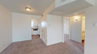 This single-floor, 2-bedroom, 2-bathroom residence offers a straightforward and functional layout designed for comfortable everyday living. The carpeted living area provides a warm, open feel, with neutral white walls and a textured ceiling that carry throughout the home. The kitchen is efficiently arranged in a galley-style configuration, featuring white cabinetry, laminate countertops, a double-basin sink beneath a window that lets in natural light, and a coil-top electric range with an overhead exhaust. Patterned vinyl flooring grounds the kitchen and connects to the adjoining areas. Both bedrooms are generously sized, outfitted with plush carpeting and ceiling fans for added comfort. The primary bedroom includes two side-by-side closets, offering ample storage. Each of the two bathrooms is clean and utilitarian in design — one features a full tub-and-shower combination with white square tile surround and chrome fixtures, while the second bathroom includes a vanity and patterned vinyl flooring. The overall layout is well-organized, with clear sightlines between the living area and kitchen, making the space feel cohesive and easy to navigate.