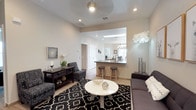 This thoughtfully designed single-story home presents a harmonious blend of comfort and functionality across its well-defined living spaces. The open-concept living room serves as the heart of the home, featuring light-toned tile flooring, recessed lighting, and a ceiling fan, anchored by a bold black-and-white patterned area rug and contemporary furnishings. A pass-through opening seamlessly connects the living area to the kitchen, enhancing the sense of openness.

The kitchen is well-equipped with light maple cabinetry, dark stone countertops, stainless steel appliances including a gas range and refrigerator, and a central island that provides additional prep space. A skylight floods the kitchen with natural light, while decorative tile backsplash accents add visual interest.

The dining room accommodates formal gatherings beneath a stylish chandelier, with a large window allowing ample natural light. A dedicated home office provides a functional workspace with wood-look tile flooring and a bright window.

The master bedroom is a serene retreat, featuring a ceiling fan, dual windows, and generous proportions, complemented by wood-look tile flooring. The bathroom includes a soaking tub with wood-toned tile surround and a vanity with stone countertops, offering a clean and relaxing environment throughout.
