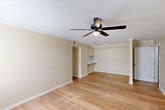 This one-bedroom, one-bathroom home in Baton Rouge, Louisiana offers a practical and comfortable single-floor layout. Light wood flooring runs throughout the home, lending warmth and a cohesive feel to each room. The combined living and dining area is the heart of the home, featuring a ceiling fan with light fixture, a textured ceiling, and neutral beige walls that create a calm, inviting atmosphere. A built-in shelf or pass-through ledge adds a functional architectural detail between the living and dining spaces, while a decorative column accent adds subtle character. Natural light enters through windows near the front entry, which includes a door with a sidelight panel. The bedroom offers a comfortable footprint with a large double-door closet, a window for natural light, and access to an additional walk-in closet with built-in shelving. The bathroom is equipped with a full tub-shower combo featuring tiled surround with a brown tile accent border, a vanity with white cabinetry, and a wall mirror. A dedicated laundry area and multiple closets throughout provide excellent storage. The kitchen completes the layout with direct access from the main living space. This home delivers efficient, well-organized living in a clean, move-in-ready condition.