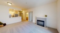 Located at 436 Broadway in the heart of downtown Tacoma, Washington, this well-designed 2-bedroom, 1-bathroom residence offers a thoughtfully efficient single-floor layout. The open-concept living area is anchored by a classic fireplace with a clean white mantel, creating a welcoming focal point. Plush carpeting runs throughout the living space, which is bathed in natural light from a sliding glass door that opens onto a private balcony overlooking the surrounding cityscape. The kitchen features light wood cabinetry, white countertops, hardwood flooring, and modern appliances, including a stainless steel refrigerator and electric range. Pendant lighting adds warmth to the kitchen's galley-style layout. Both bedrooms are carpeted and feature neutral tones, individual windows with blinds, and baseboard heating. The primary bedroom includes a sliding-door closet with built-in shelving. The full bathroom is finished with hardwood flooring, a vessel sink vanity with light wood cabinetry, a tub-shower combination, and a convenient in-unit stacked washer and dryer. Clean lines, a neutral palette, and functional design define the overall ambiance of this downtown Tacoma residence.