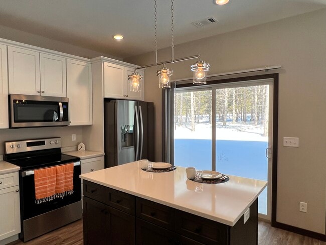Cocina con isla central, encimera de cuarzo, puerta corrediza que da a un patio cubierto. - 300 Thumper Lodge Rd