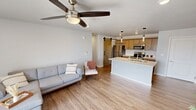 This contemporary 830 square foot apartment maximizes space and functionality. The single-floor layout features one bedroom, two bathrooms, and a dedicated office space, ideal for modern living or working from home. The heart of the home is an open-concept kitchen and living area, showcasing light wood cabinetry, stainless steel appliances, and a sleek design that seamlessly blends cooking and entertainment spaces.

The living room boasts a minimalist aesthetic with comfortable seating and ample natural light. The bedroom, spanning 130 square feet, offers a serene retreat with a large window and modern ceiling fan. Additional features include a separate laundry room with full-sized appliances, built-in closets for storage, and climate control via wall-mounted air conditioning units.

A standout feature is the private balcony, offering scenic views of the surrounding landscape. The exterior showcases modern architecture with clean lines and a neutral color palette. This well-designed apartment combines style and practicality, perfect for those seeking a contemporary living space in a multi-unit complex.