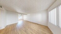 Located at 6363 Beadnell Way in San Diego's Clairemont Mesa neighborhood, this 2-bedroom, 1-bathroom residence offers a clean, modern aesthetic across a thoughtfully arranged single-floor layout. Light wood-tone flooring runs throughout, complementing the crisp white walls and textured ceilings found in every room.

The open living and dining area is bright and airy, with natural light filtering through a large window and a ceiling fan adding comfort. The space flows naturally into the kitchen, which features white shaker cabinetry, white countertops, a single-basin sink with a matte black faucet, and a full suite of black appliances including a refrigerator, range, microwave, and dishwasher.

Both bedrooms are well-proportioned and include sliding-door closets and windows dressed with vertical blinds that allow for adjustable natural light. The primary bedroom offers generous space for furnishings. A hallway connects the bedrooms to the shared bathroom, which stands out with its wide dual-sink vanity, white cabinetry with matte black hardware, dual mirrors with integrated lighting, and wood-tone flooring — a notably upscale finish for a shared bath. The overall ambiance is fresh, clean, and move-in ready.