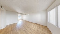 Located at 6363 Beadnell Way in San Diego's Clairemont Mesa neighborhood, this 2-bedroom, 1-bathroom residence offers a clean, modern aesthetic across a thoughtfully arranged single-floor layout. Light wood-tone flooring runs throughout, complementing the crisp white walls and textured ceilings found in every room.

The open living and dining area is bright and airy, with natural light filtering through a large window and a ceiling fan adding comfort. The space flows naturally into the kitchen, which features white shaker cabinetry, white countertops, a single-basin sink with a matte black faucet, and a full suite of black appliances including a refrigerator, range, microwave, and dishwasher.

Both bedrooms are well-proportioned and include sliding-door closets and windows dressed with vertical blinds that allow for adjustable natural light. The primary bedroom offers generous space for furnishings. A hallway connects the bedrooms to the shared bathroom, which stands out with its wide dual-sink vanity, white cabinetry with matte black hardware, dual mirrors with integrated lighting, and wood-tone flooring — a notably upscale finish for a shared bath. The overall ambiance is fresh, clean, and move-in ready.