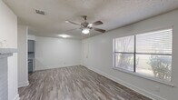 Located at 121 S Hampton Rd in Crowley, TX, this two-story home offers 2 bedrooms and 2 bathrooms across two floors. The main level comprises the majority of the living space, encompassing the living room, kitchen, a bathroom, and hallways, while the upper level provides additional private accommodations.

The living room is bright and open, featuring wood-look laminate flooring, a ceiling fan with light fixture, a window with blinds for natural light, and a standout gray brick fireplace that adds warmth and character to the space. Textured ceilings are consistent throughout the home.

The galley-style kitchen is well-appointed with gray cabinetry, granite-style countertops, a double-basin sink, a white electric range, and a white refrigerator — all complemented by the same durable wood-look flooring.

Both bedrooms are comfortably sized, each outfitted with ceiling fans, windows with natural light, and louvered bifold closet doors for ample storage. The primary bedroom offers direct access to an en-suite bathroom. Both bathrooms feature tub/shower combinations, granite-style vanity countertops, and clean white finishes.

A staircase connects the two floors, and hallways provide efficient circulation throughout. The home's neutral color palette and consistent flooring create a cohesive, move-in-ready aesthetic.