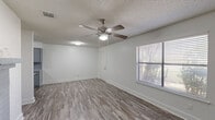 Located at 121 S Hampton Rd in Crowley, TX, this two-story home offers 2 bedrooms and 2 bathrooms across two floors. The main level comprises the majority of the living space, encompassing the living room, kitchen, a bathroom, and hallways, while the upper level provides additional private accommodations.

The living room is bright and open, featuring wood-look laminate flooring, a ceiling fan with light fixture, a window with blinds for natural light, and a standout gray brick fireplace that adds warmth and character to the space. Textured ceilings are consistent throughout the home.

The galley-style kitchen is well-appointed with gray cabinetry, granite-style countertops, a double-basin sink, a white electric range, and a white refrigerator — all complemented by the same durable wood-look flooring.

Both bedrooms are comfortably sized, each outfitted with ceiling fans, windows with natural light, and louvered bifold closet doors for ample storage. The primary bedroom offers direct access to an en-suite bathroom. Both bathrooms feature tub/shower combinations, granite-style vanity countertops, and clean white finishes.

A staircase connects the two floors, and hallways provide efficient circulation throughout. The home's neutral color palette and consistent flooring create a cohesive, move-in-ready aesthetic.