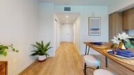 Located at 1642 E Florence Ave in Los Angeles, CA, this efficiently designed studio unit makes smart use of its single-floor layout. Light wood-style flooring runs throughout, unifying the space and lending it a warm, contemporary feel.

The kitchen is a standout feature, showcasing floor-to-ceiling warm wood cabinetry with ample storage, dark stone countertops, a stainless steel sink, and a full suite of stainless steel appliances including a range with hood and a full-sized refrigerator. A deep blue tile backsplash behind the range adds a bold design accent. A dining table positioned alongside the kitchen creates a natural eat-in area, making the kitchen the functional heart of the unit.

The entrance corridor is clean and inviting, with recessed lighting, crisp white walls, and the same light wood flooring that flows from the main living area. The transition into the space feels open and uncluttered.

The bathroom is accessible via a full-panel door and features a clean, minimalist design with white walls, light wood-style flooring, a wall-mounted toilet, and a shower with a curtain enclosure. Recessed lighting keeps the room bright.

The living and sleeping area benefits from a large window that invites natural light, creating an airy atmosphere within this compact yet complete single-floor residence.