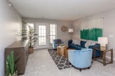 This single-floor residence offers a thoughtfully designed layout that balances comfort and functionality. The open-concept living and dining area forms the heart of the home, featuring plush wall-to-wall carpeting, neutral tones, and a ceiling fan that enhances the airy, welcoming atmosphere. The living room provides generous space for seating and entertaining, flowing seamlessly into a dedicated dining area. The kitchen is outfitted with white upper cabinetry, gray lower cabinets, light quartz countertops, and wood-look luxury vinyl plank flooring. A full-size refrigerator anchors the space, and a walk-through area leads to a laundry closet equipped with a washer and dryer. The primary bedroom is a spacious retreat highlighted by a charming arched window that fills the room with natural light, soft carpeting, and access to multiple closets, offering ample storage. An additional bedroom features the same neutral carpeting and a clean, minimalist finish. Both bathrooms are finished with wood-look flooring and include a combined tub and shower enclosed by sliding glass doors, a toilet, and a vanity with countertop space. Throughout the home, a consistent soft gray palette and clean white trim create a cohesive, modern aesthetic.