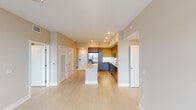 Located at Alexan Park 82nd in Doral, Florida, Unit 2407 presents a thoughtfully designed, single-floor residence with a clean, contemporary aesthetic throughout. Light-toned large-format tile flooring runs seamlessly across the main living areas, enhancing the sense of openness and continuity.

The kitchen is a standout feature, equipped with stainless steel appliances including a side-by-side refrigerator with ice maker, an electric range, and a built-in microwave. Two-tone cabinetry — combining warm wood uppers with sleek gray lowers — pairs with bright white countertops and a central island, making the space as functional as it is visually striking. Recessed lighting adds a polished finish.

The open living and dining area is bathed in natural light from large windows and a glass balcony door, which provides outdoor views of the surrounding Doral neighborhood. A ceiling fan adds comfort to the airy space.

The bedrooms are generously proportioned, each featuring large windows with neighborhood views, ceiling fans, and ample closet storage including louvered-door closets. The primary bathroom offers a wide double-vanity with white quartz countertops, modern fixtures, and a frameless glass walk-in shower. A secondary full bathroom mirrors the same refined, neutral palette with a glass-enclosed shower and clean tile finishes throughout.