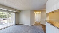 Located at 100 Piccadilly Loop in Yorktown, Virginia, this single-floor, 2-bedroom, 2-bathroom residence offers a practical and comfortable layout. The open living area features neutral-toned carpet, textured ceilings, and a sliding glass door that leads to a private balcony, filling the space with natural light and views of the surrounding greenery. A pass-through connects the living area to the galley-style kitchen, which is equipped with stainless steel appliances, white shaker cabinetry, granite-style countertops, and wood-look flooring — creating a clean and functional cooking space. A dedicated dining room adds additional versatility to the layout. The primary bedroom is a generously sized retreat with a window overlooking the outdoors, plush carpet, and ample closet storage. The second bedroom also features carpet flooring, a large closet, and a bright window. Two full bathrooms serve the residence — one with a shower stall and wood-look flooring, and the other with a tub/shower combination, white vanity, and matching flooring. Additional highlights include four total closets for abundant storage and a dedicated in-unit laundry area, rounding out this well-appointed home.