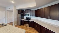 Located in Fort Mill, SC, this single-floor residence offers a thoughtfully designed layout with quality finishes throughout. The kitchen is a standout feature, showcasing rich dark cabinetry, granite countertops, a classic white subway tile backsplash, and a full suite of stainless steel appliances including a refrigerator, range, and built-in microwave. Generous counter space extends along the perimeter, providing ample room for meal preparation. The main living areas are finished with warm hardwood-style flooring that flows through the hallways and common spaces. Bedrooms feature plush carpeting underfoot and neutral wall tones, creating a calm and comfortable atmosphere. One bedroom includes a ceiling fan and multiple windows that invite natural light and outdoor views. A spacious walk-in closet with wire shelving provides excellent storage capacity. The bathrooms are well-appointed with dark vanities, white countertops, large mirrors, and stylish vanity lighting. A dedicated laundry room houses a full-size washer and dryer with additional wire shelving above. Connecting the bedrooms and bathrooms is a well-lit hallway with clean, bright paneled doors. The overall design reflects a modern and functional aesthetic suited to everyday living.