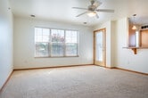 Located at 188 Cannery Pl in Sun Prairie, Wisconsin, this 2-bedroom, 2-bathroom single-floor home offers a practical and comfortable layout. The open-concept living area seamlessly connects the living room, dining room, and kitchen, all unified by neutral carpet, warm oak trim, and ceiling fans throughout. The kitchen is well-appointed with honey-toned oak cabinetry, laminate countertops, tile flooring, black appliances including a range, microwave, and refrigerator, plus a dishwasher and a dedicated pantry for additional storage. Natural light filters in through windows with views of surrounding greenery. The spacious primary bedroom features plush carpeting, a ceiling fan, a large window, and a generous walk-in closet with wire shelving. The second bedroom is equally comfortable with a ceiling fan, carpeting, and a sliding-door closet. Both bathrooms are finished with tile flooring, oak vanity cabinetry, and large mirrors. The home also includes an in-unit laundry area, five closets total for excellent storage capacity, and access to a private patio. The consistent use of warm oak wood tones and clean white walls throughout creates a cohesive and welcoming atmosphere.