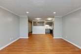 This single-floor unit offers a thoughtfully designed layout that balances open living with functional spaces. The main living area features warm hardwood-style flooring, soft gray walls, crown molding, and a textured ceiling with recessed lighting, creating a bright and welcoming atmosphere.

The kitchen is open to the living area via a half-wall pass-through, making it ideal for entertaining and everyday living. It is equipped with gray shaker-style cabinetry, a classic white subway tile backsplash, a stainless steel double-basin sink with a modern pull-down faucet, and stainless steel appliances including an electric range. The layout maximizes counter and storage space efficiently.

The bedroom is a comfortable, well-proportioned room with the same hardwood-style flooring, crown molding, and a textured ceiling. A window fitted with blinds allows natural light to filter in, and a wall-mounted climate control unit provides individual temperature management. Closet access is conveniently located within the room.

The bathroom features a full tub-and-shower combination, a white vanity with a single-basin sink, a framed mirror with brushed nickel accents, and distinctive dark geometric-patterned tile flooring that adds a stylish contrast to the neutral walls. Overall, the space presents a clean, modern aesthetic throughout.