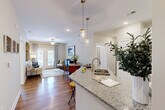 Located at 1220 Pleasant Ridge Rd in Greensboro, NC, this single-story 2-bedroom, 1-bathroom home offers a thoughtfully designed open-concept layout. The kitchen is a standout feature, showcasing granite countertops, white shaker cabinetry, a subway tile backsplash, stainless steel appliances, and an island with pendant lighting that flows seamlessly into the living area. The living room is bright and welcoming, with hardwood-style flooring, a ceiling fan, and French doors that open to a private patio with outdoor views. Both bedrooms are comfortably sized, with the primary bedroom offering ample space, a ceiling fan, and generous natural light from large windows. The full bathroom features a tub/shower combination with white tiled surround. A dedicated laundry room houses a full-size side-by-side washer and dryer. Abundant storage is provided through five closets throughout the home. Neutral wall tones, recessed lighting, and consistent flooring create a cohesive, modern ambiance throughout the entire residence.