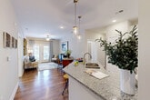 Located at 1220 Pleasant Ridge Rd in Greensboro, NC, this single-story 2-bedroom, 1-bathroom home offers a thoughtfully designed open-concept layout. The kitchen is a standout feature, showcasing granite countertops, white shaker cabinetry, a subway tile backsplash, stainless steel appliances, and an island with pendant lighting that flows seamlessly into the living area. The living room is bright and welcoming, with hardwood-style flooring, a ceiling fan, and French doors that open to a private patio with outdoor views. Both bedrooms are comfortably sized, with the primary bedroom offering ample space, a ceiling fan, and generous natural light from large windows. The full bathroom features a tub/shower combination with white tiled surround. A dedicated laundry room houses a full-size side-by-side washer and dryer. Abundant storage is provided through five closets throughout the home. Neutral wall tones, recessed lighting, and consistent flooring create a cohesive, modern ambiance throughout the entire residence.