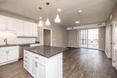 This 2-bedroom, 3-bathroom single-floor residence offers a comfortable and modern living environment with consistent, quality finishes throughout. The open-concept kitchen and living area serves as the heart of the home, featuring white shaker-style cabinetry, a classic white subway tile backsplash, dark granite countertops, and a central island with pendant lighting overhead. Stainless steel appliances complete the kitchen, which flows seamlessly into the living room. The living room is finished with rich wood-look flooring and connects to a private balcony through sliding glass doors, allowing for natural light and outdoor access. Both bedrooms are carpeted and well-proportioned, with the spacious primary bedroom offering generous room to accommodate a full furniture arrangement. Each bedroom benefits from window views and dedicated closet space. The three bathrooms are finished with white cabinetry, granite countertops, wood-look flooring, and brushed nickel hardware. One bathroom includes a full soaking tub with shower surround, while the others feature clean, functional layouts with ample vanity storage. Neutral wall tones and consistent flooring materials create a cohesive, move-in-ready aesthetic throughout the entire residence.