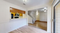 This two-story home offers a well-organized layout spread across two floors, providing a practical and comfortable living environment. The main level features light hardwood-style flooring throughout, creating a clean and cohesive aesthetic. The kitchen is designed with a pass-through breakfast bar, warm wood cabinetry, black appliances including a refrigerator, range, and microwave, along with ample counter space and an adjacent dining area. The living room is a standout space, highlighted by a brick-framed fireplace flanked by two windows that allow natural light to fill the room. A ceiling fan adds comfort, while a staircase leads to the upper floor. Three full bathrooms are present throughout the home, each featuring wood-toned vanities, light countertops, and tiled tub-shower combinations with hardwood-style flooring. The upper level is home to the spacious primary bedroom, which features vaulted ceilings, soft carpeting, a ceiling fan, and a window offering natural light. An en-suite vanity area connects directly to the bedroom. Additional features include multiple closets, a dedicated laundry area, a utility room, a patio for outdoor access, and hallways connecting the functional spaces throughout both floors.