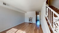 This two-story residence offers a well-organized layout designed for comfortable everyday living. The main level welcomes you through a front entry with abundant natural light streaming through large windows, illuminating the warm hardwood-style flooring that extends throughout the common areas. The living room is generously proportioned, featuring textured ceilings, neutral gray walls, and an open sightline that creates an airy, inviting atmosphere. The kitchen is efficiently designed with white shaker-style cabinetry, granite-look countertops, a stainless steel sink, and black appliances including a refrigerator and dishwasher. A convenient half bathroom with a pedestal sink and tiled backsplash is also located on the main floor. A staircase with a white railing connects the two levels, adding a classic architectural element to the space. Upstairs, the bedrooms are carpeted for comfort and feature ceiling fans, natural light from windows with blinds, and closets with built-in hanging rods for ample storage. The full bathroom on this level includes a tub-shower combination, white cabinetry with granite-look countertops, hardwood-style flooring, and a clean, bright finish. Overall, the space presents a practical and cohesive design throughout.