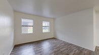 This 2-bedroom, 1-bathroom single-floor home offers a clean, functional layout designed for comfortable everyday living. Wood-look flooring runs consistently throughout the space, providing a cohesive and low-maintenance aesthetic. Crisp white walls and neutral tones create a bright, open atmosphere across every room.

The living room is generously proportioned, featuring multiple windows fitted with blinds that allow natural light to fill the space while offering privacy. The kitchen is efficiently designed in a galley configuration, with white cabinetry, light countertops, a stainless steel sink, and white appliances including a range and oven. Ample upper and lower cabinet storage adds to its practicality.

The primary bedroom is a well-sized retreat with dual windows offering outdoor views of greenery, while the second bedroom also includes a window and benefits from a ceiling fan with a light fixture. One bedroom features a built-in sliding-door closet, adding convenient storage. A hallway connects the bedrooms to the full bathroom, which includes a tub and shower combination finished with classic white subway tile surround. The unit also includes a dedicated laundry area. Overall, the home presents a clean, move-in ready environment with consistent finishes throughout.