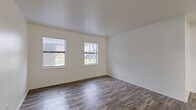 This 2-bedroom, 1-bathroom single-floor home offers a clean, functional layout designed for comfortable everyday living. Wood-look flooring runs consistently throughout the space, providing a cohesive and low-maintenance aesthetic. Crisp white walls and neutral tones create a bright, open atmosphere across every room.

The living room is generously proportioned, featuring multiple windows fitted with blinds that allow natural light to fill the space while offering privacy. The kitchen is efficiently designed in a galley configuration, with white cabinetry, light countertops, a stainless steel sink, and white appliances including a range and oven. Ample upper and lower cabinet storage adds to its practicality.

The primary bedroom is a well-sized retreat with dual windows offering outdoor views of greenery, while the second bedroom also includes a window and benefits from a ceiling fan with a light fixture. One bedroom features a built-in sliding-door closet, adding convenient storage. A hallway connects the bedrooms to the full bathroom, which includes a tub and shower combination finished with classic white subway tile surround. The unit also includes a dedicated laundry area. Overall, the home presents a clean, move-in ready environment with consistent finishes throughout.