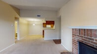 This single-floor residence at 1704 Dublin Blvd in Colorado Springs, Colorado offers a well-designed layout with functional living spaces throughout. The living room is a standout area, featuring vaulted ceilings, plush carpet flooring, and a classic brick fireplace with a white mantle. Large windows and a glass-panel door flood the space with natural light and provide outdoor views, creating an open and airy ambiance. The living area flows seamlessly into a dining nook, illuminated by a pendant light fixture, and connects to the kitchen via a pass-through counter. The galley-style kitchen is equipped with rich warm-toned wood cabinetry, light countertops, white appliances including a range, microwave, refrigerator, and dishwasher, along with hardwood-style flooring that adds warmth and durability. The bedrooms are carpeted and generously sized, with one featuring a ceiling fan and ample natural light from windows with blinds. The bathroom includes a single-sink vanity with wood cabinetry, a tub-shower combination with tile surround, and hardwood-style flooring. Throughout the residence, neutral wall tones and textured ceilings contribute to a clean, comfortable atmosphere.
