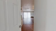 This two-story home offers a well-organized layout spread across two floors of comparable size. The main level features a combined kitchen and living room area, where rich hardwood-style flooring runs throughout. The living room is a standout space, highlighted by a striking exposed brick accent wall that adds character and warmth, along with a sliding glass door fitted with vertical blinds that opens to a private outdoor area, allowing natural light to fill the room. The kitchen is equipped with dark cabinetry, a double-basin sink, ample counter space, and a full-size refrigerator, with a window above the sink providing additional light. Tile flooring at the entry transitions seamlessly into the wood-style flooring of the main living areas. The two bathrooms are clean and functional, one featuring a tiled shower-tub combination, wood-style flooring, and a vanity with a wide mirror. Upstairs, both bedrooms are carpeted and include ceiling fans with light fixtures and windows for natural light. The primary bedroom is a comfortable size, and a dedicated walk-in closet with dual hanging rods and built-in shelving provides generous storage. The second bedroom also features carpeting and a ceiling fan, offering a versatile and practical space.