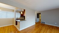 Located at 1 John F Kennedy Blvd in Somerset, NJ, this well-appointed single-floor residence offers a thoughtfully designed layout with consistent warm-toned hardwood flooring throughout the main living areas. The open living room is bright and spacious, featuring large sliding glass doors fitted with vertical blinds that fill the space with natural light and provide direct access to an outdoor patio area.

The galley-style kitchen is a functional highlight, featuring rich dark wood cabinetry, striking dark granite countertops with bold veining, a classic tile backsplash, and a full suite of stainless steel appliances including a gas range, microwave, refrigerator, and dishwasher. A peninsula counter connects the kitchen to the main living area, creating a convenient pass-through that enhances the open feel.

The bedroom is generously sized with a closet, neutral-toned walls, and a window with blinds that allows for ample natural light. The bathroom is clean and modern, featuring a tiled tub-shower combination with decorative accent tiles and light wood-look flooring. A dedicated laundry area houses a full-sized washer and dryer beneath dark wood overhead cabinetry, adding everyday convenience. Clean white trim and neutral gray walls create a cohesive, move-in ready aesthetic throughout the entire unit.