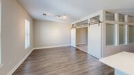 Located at 7131 Arlington Rd in Bethesda, Maryland, Unit 535 is a thoughtfully designed single-floor residence that makes excellent use of its space. The interior is finished with warm-toned hardwood-style flooring throughout, complemented by neutral walls that create a bright, cohesive aesthetic.

The entryway features a distinctive interior glass-panel partition wall, lending an open, modern architectural character while allowing natural light to flow through the space. A hallway leads into the main living area, which benefits from a window with views of the surrounding neighborhood and is enhanced by a stylish sliding barn door that provides access to the closet.

The kitchen is a standout feature, outfitted with crisp white shaker cabinetry, quartz countertops, a light green subway tile backsplash, and a full suite of stainless steel appliances including a gas range, built-in microwave, dishwasher, and refrigerator. A kitchen island adds additional prep and dining space, while pendant lighting above adds a refined touch.

The bathroom is clean and well-appointed, featuring a tiled tub-shower combo, a white vanity with a large mirror, and hardwood-style flooring that ties seamlessly to the rest of the unit. The overall ambiance is modern, light, and functional, making this Bethesda residence an efficient and attractive living space.