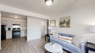 Located at 2158 30th St in Greeley, Colorado, this single-floor, 2-bedroom, 1-bathroom home offers a thoughtfully organized layout that maximizes every inch of its compact footprint. The living room serves as the heart of the space, featuring light-toned luxury vinyl plank flooring, a textured ceiling, and a large picture window dressed with vertical blinds that floods the room with natural light and offers a pleasant outdoor view of surrounding greenery. The open sightline into the kitchen creates a seamless flow between living and cooking areas. The kitchen is outfitted with white shaker-style cabinetry, granite-look countertops, and black appliances including a full-size refrigerator, electric range with overhead ventilation, and dishwasher — all set on matching LVP flooring. Both bedrooms feature soft carpeting and closet storage, with the primary bedroom offering a notably generous layout. The full bathroom is clean and functional, showcasing a white vanity with storage, wood-look flooring, and a tub-shower combination with tiled surround. Throughout the home, a neutral white and grey color palette creates a bright, cohesive ambiance well-suited for comfortable everyday living.