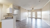 Located at 500 W Cartwright Rd in Balch Springs, TX, this single-story, 3-bedroom, 2-bathroom home offers a well-organized and functional layout. The open-concept living room and kitchen area serves as the heart of the home, featuring rich wood-look hardwood flooring, crown molding, and a ceiling fan with light fixture. Multiple windows along the front wall allow natural light to fill the space, with a front entry door providing direct access. The kitchen runs along a galley-style corridor with white cabinetry, stone-look countertops, a peninsula with a double sink, and stainless steel appliances including a refrigerator, range, and microwave. The three bedrooms are finished with plush carpet and ceiling fans. The primary bedroom includes a walk-in closet with built-in shelving. Two additional bedrooms offer comfortable proportions with closets and natural light. The two bathrooms feature white cabinetry, stone countertops, large mirrors, and tiled tub-shower combinations with wood-look flooring. A dedicated laundry area includes washer/dryer hookups and overhead shelving. Two hallways connect the bedrooms and common areas, contributing to a smooth and practical flow throughout the home.